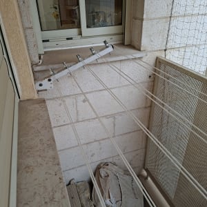 מתקן כביסה מותקן על קיר מרפסת עם חבלים