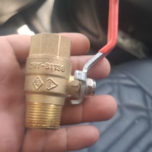 שסתום פליז עם ידית אדומה בתחום האינסטלציה