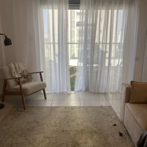 חדר עם וילון לבן, כורסה ושולחן קטן