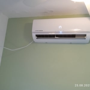 מזגן מותקן על קיר ירוק עם תצוגת טמפרטורה