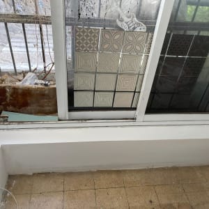 קיר גבס צבוע בלבן ליד חלון עם אריחים דקורטיביים