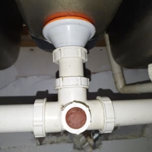 צינור פלסטיק לבן עם מחבר טי מתחת לכיור