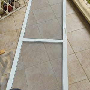 מסגרת רשת הזזה מאלומיניום מונחת על הרצפה במהלך עבודת תיקון רשתות