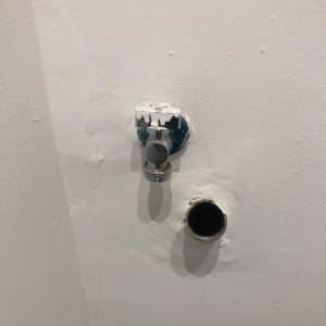 שסתום מים וצינור בקיר לבן