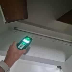 יד מחזיקה מכשיר מדידה מתחת למדף