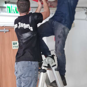 שני אנשים מתקנים צינור עם מפתח צינורות אדום