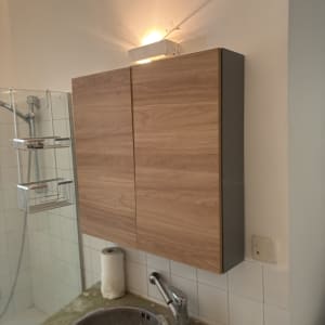 ארון עץ מעל כיור בחדר אמבטיה עם תאורה עליונה