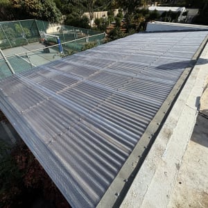 גג מתכת מותקן מעל מבנה ליד מגרש ספורט