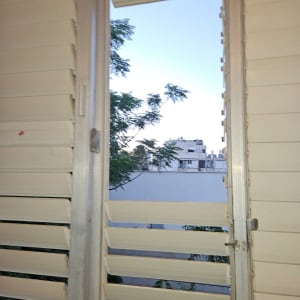 תריסים פתוחים עם נוף של עצים ובניינים ברקע