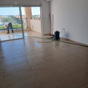 חדר עם רצפה רטובה, אדם מנקה מרפסת
