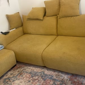 ספה צהובה עם כריות ושמיכה על הרצפה