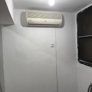 מזגן מותקן על קיר לבן עם חוט חשמל