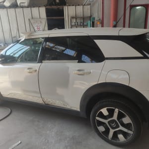 רכב לבן בתהליך תיקון פחחות במוסך