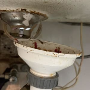 צנרת מתחת לכיור עם סימני חלודה ולכלוך