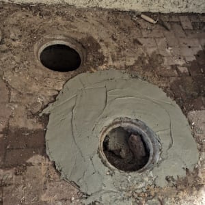 שני פתחים עגולים ברצפה עם בטון סביבם