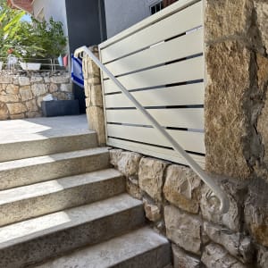 מעקה מתכת לבן ליד מדרגות אבן