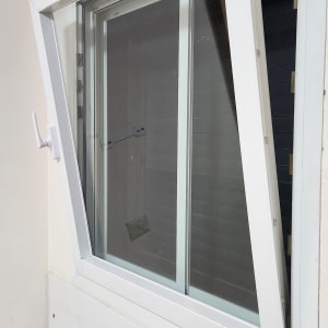 חלון פתוח עם תריסים לבנים על קיר פנימי