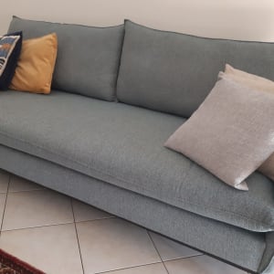 ספה אפורה עם כריות צבעוניות על רצפת אריחים