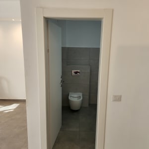 אסלה בחדר שירותים עם קיר אריחים אפור