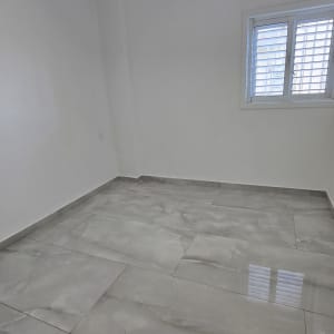 חדר ריק עם רצפת אריחים ומזגן על הקיר