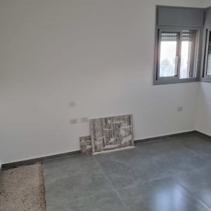 קיר מושלם שנצבע בלבן בחדר ריק עם רצפת ריצוף אפורה