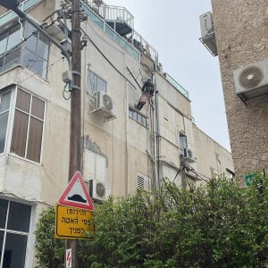 אדם תלוי על חבלים מבצע עבודות גובה על בניין