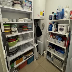 מדפים עם כלי מטבח, חומרי ניקוי ומיכלים מאורגנים