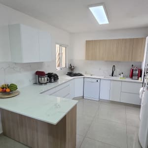 מטבח מודרני עם ארונות לבנים ומשטח עבודה מעץ