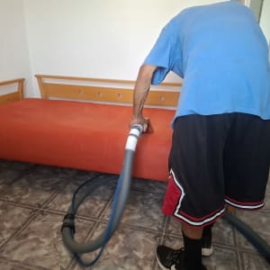 אדם מנקה ספה עם שואב אבק