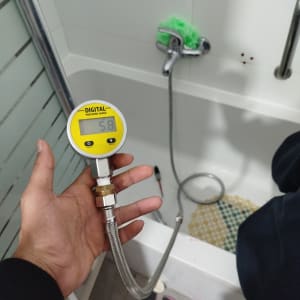 מד לחץ דיגיטלי ליד אמבטיה עם ברז ומברשת ירוקה