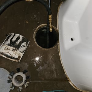 צינור שחור, מברג ומברשת ליד חור ברצפה