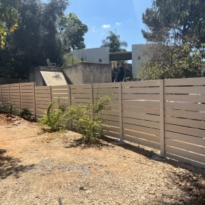 גדר עץ לבנה עם צמחים מסביב