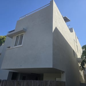 בניין מגורים עם קירות חיצוניים בהירים ועצים מסביב