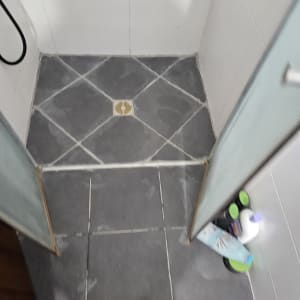רצפת מקלחת עם ניקוז ומוצרי ניקוי בפינה