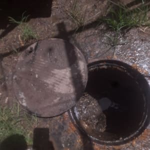 פתח ביוב פתוח עם מכסה מונח בצד