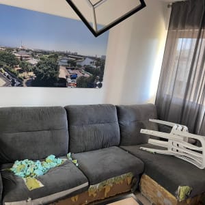 ספה אפורה עם ריפוד קרוע ומילוי חשוף