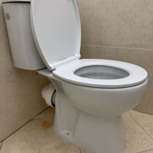 אסלה לבנה בחדר אמבטיה עם קירות אריחים