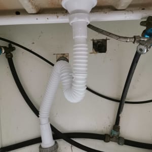 צינור ניקוז לבן מתחת לכיור עם חיבורים