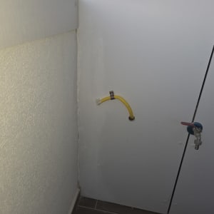 צינור גז צהוב וברז על קיר לבן