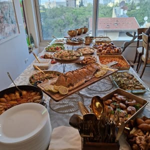 שולחן ערוך עם מגוון מנות קייטרינג, כולל סלטים, לחמים ומאפים.