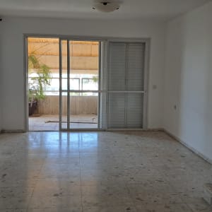 חדר ריק עם רצפת שיש ודלת זכוכית למרפסת