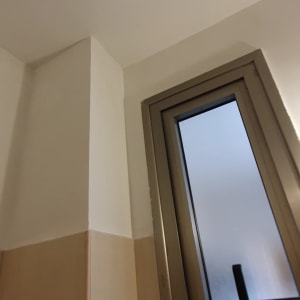 קיר צבוע לבן ליד חלון עם מסגרת מתכת