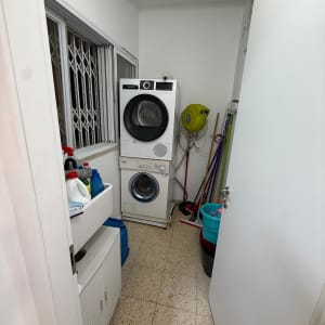 חדר כביסה עם מכונת כביסה ומייבש, דלי ומטאטאים