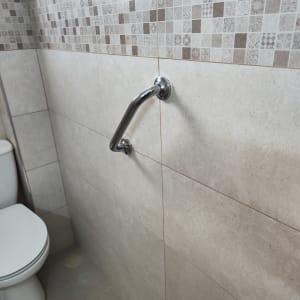ידית אחיזה מתכתית מותקנת על קיר אריחים בחדר אמבטיה