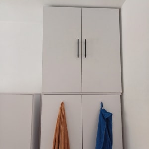 ארון עץ עם ידיות שחורות ומגבות תלויות