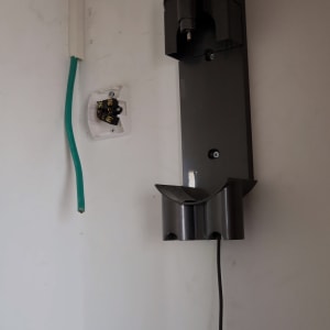 חוט חשמל ירוק ושקע חשמלי פתוח על קיר