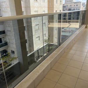 מרפסת עם רצפה נקייה ומעקה זכוכית