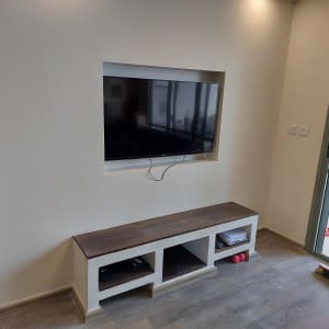 טלוויזיה תלויה על קיר גבס עם מדף תחתון