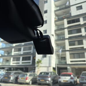 מצלמת רכב מותקנת על שמשת רכב עם בניין ברקע
