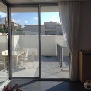 וילון לבן תלוי על חלון זכוכית גדול